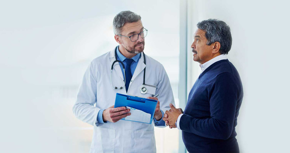 A male provider speaking to a man in a suit.