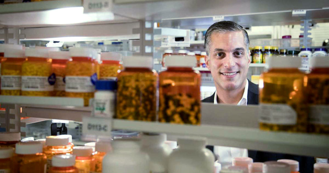 Shaun Noorian looking over a shelf of medication.