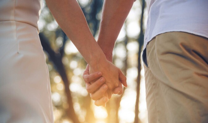 A couple holding hands outdoors.