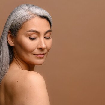 middle aged woman with long gray hair and a copper background to discuss copper peptides