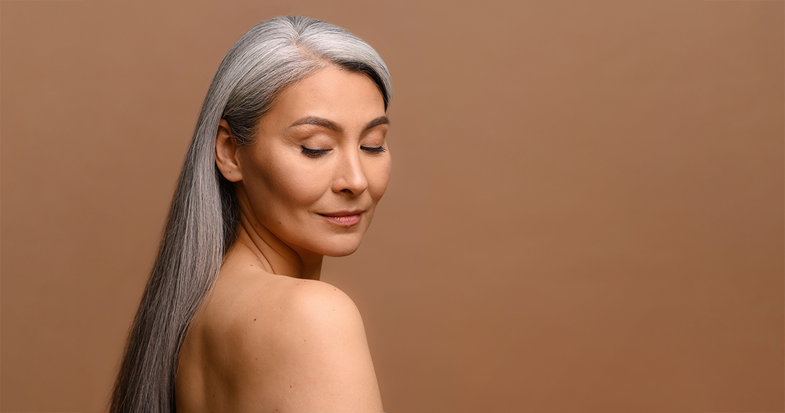 middle aged woman with long gray hair and a copper background to discuss copper peptides